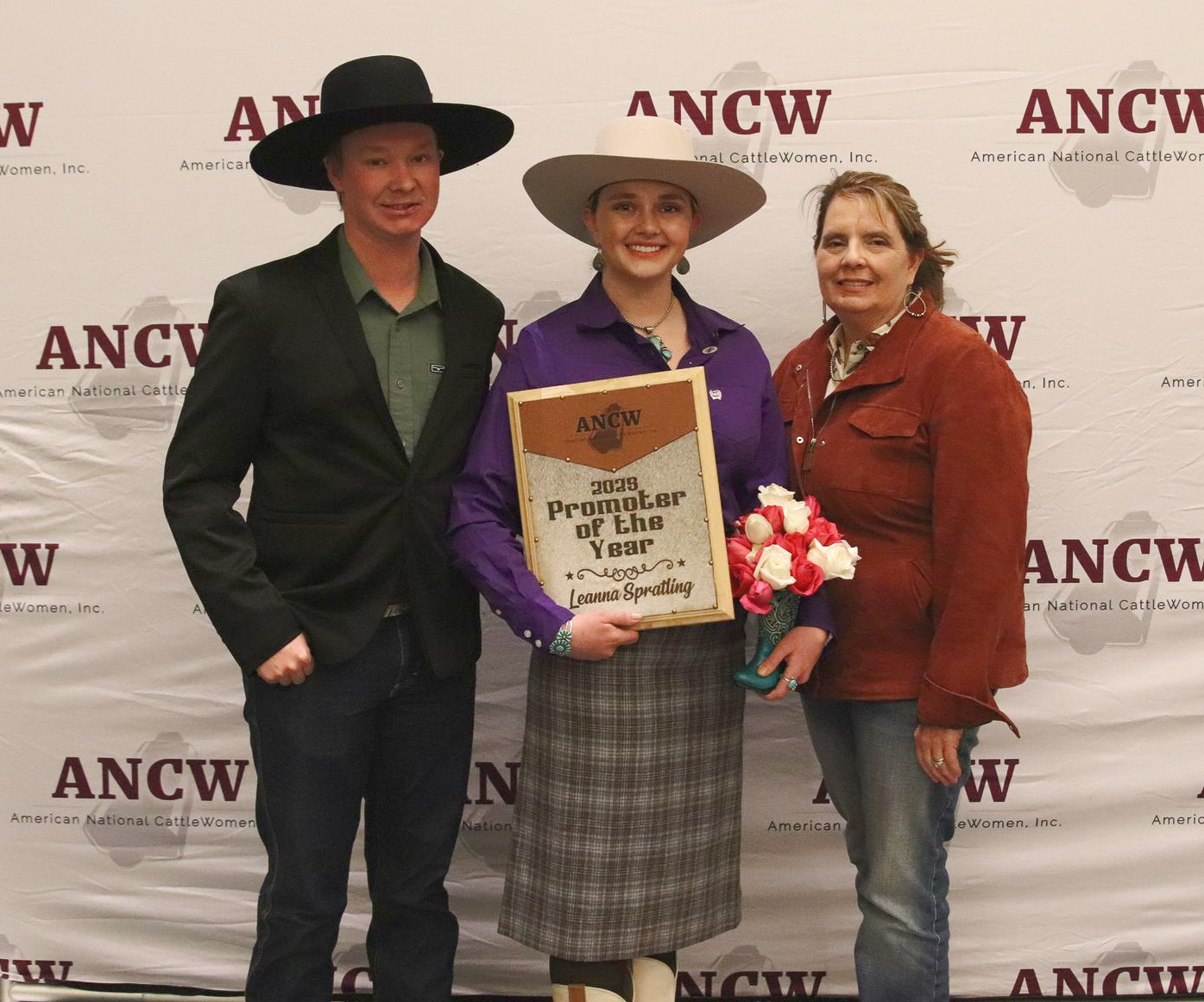 Five women smiling, posing behind illuminated 