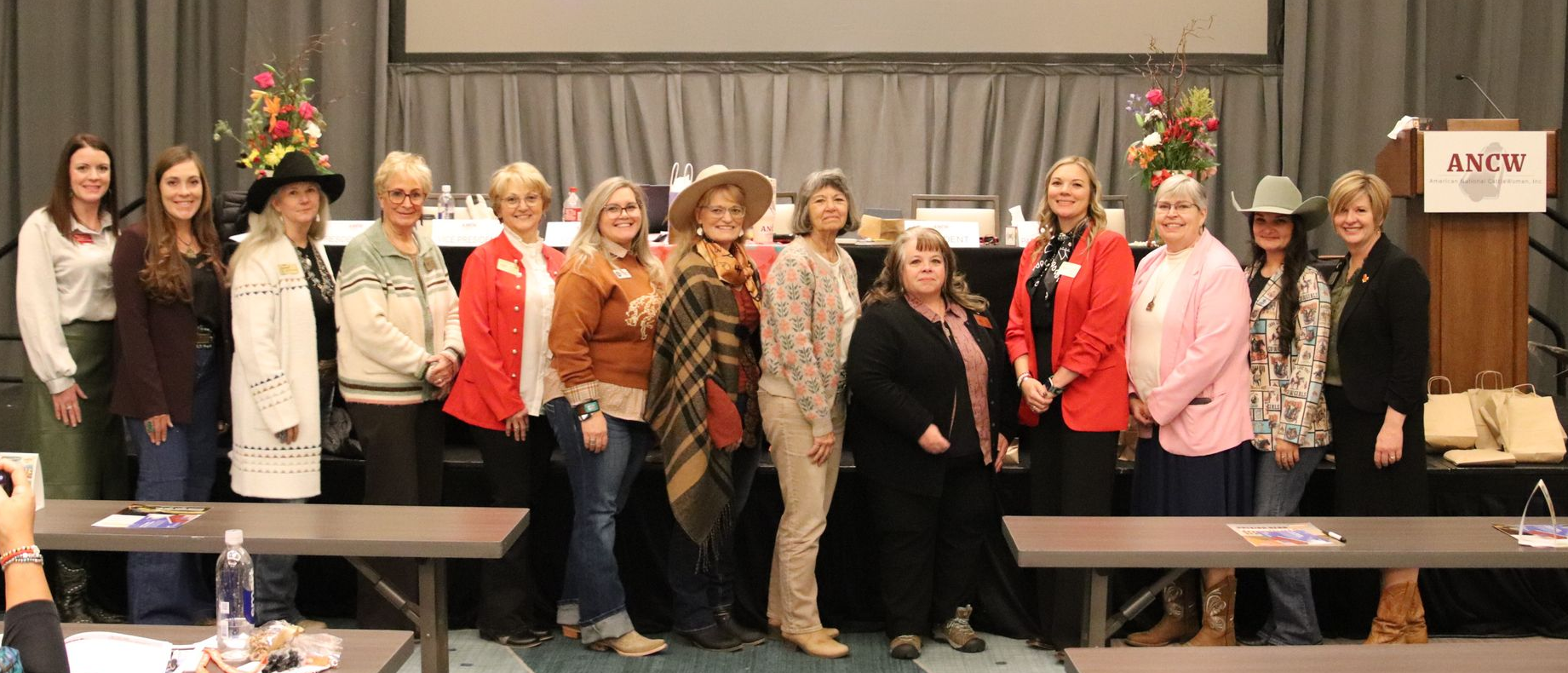 Group of women standing and sitting; in front of wood doors; some smiling.