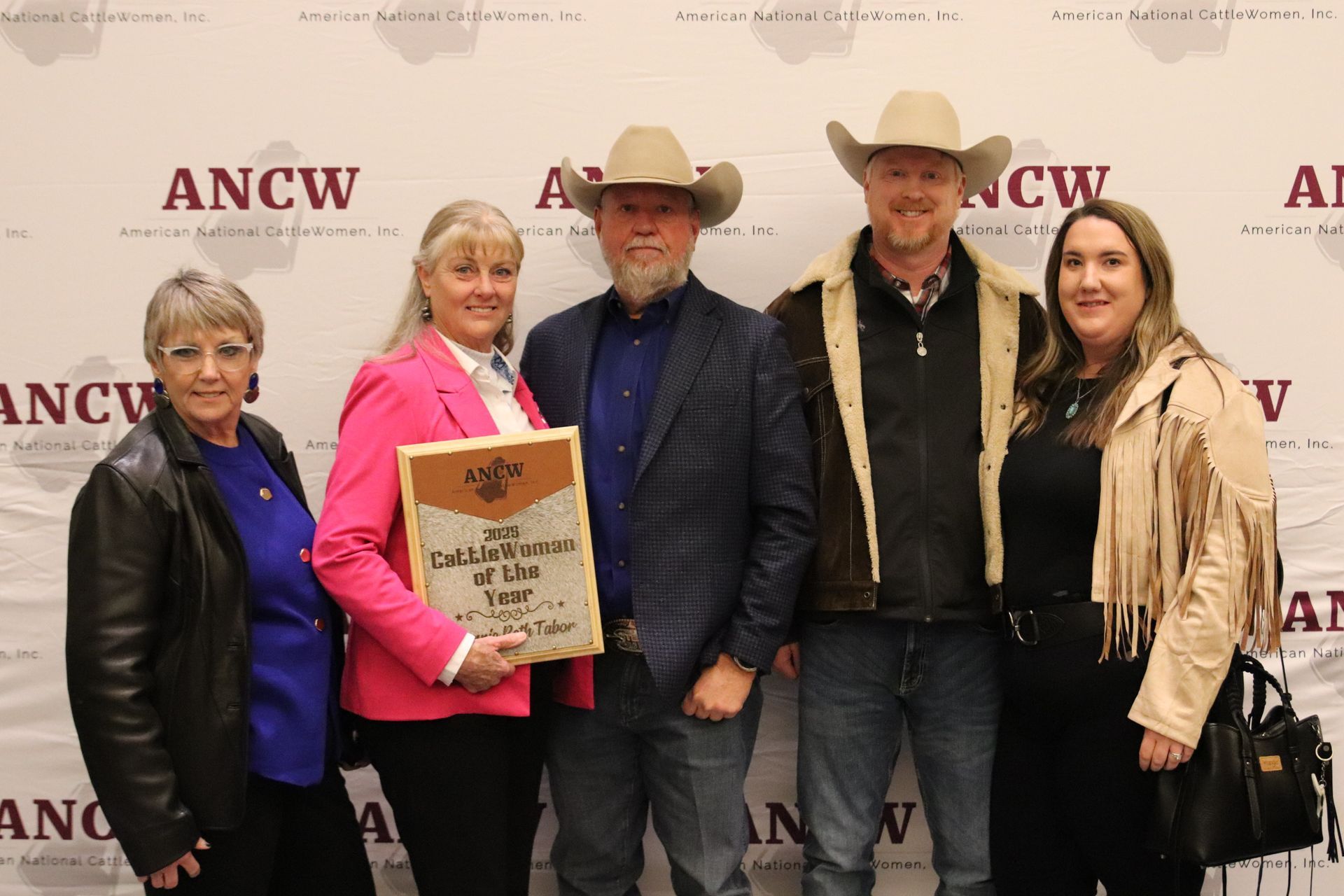 Five women smiling, posing behind illuminated 
