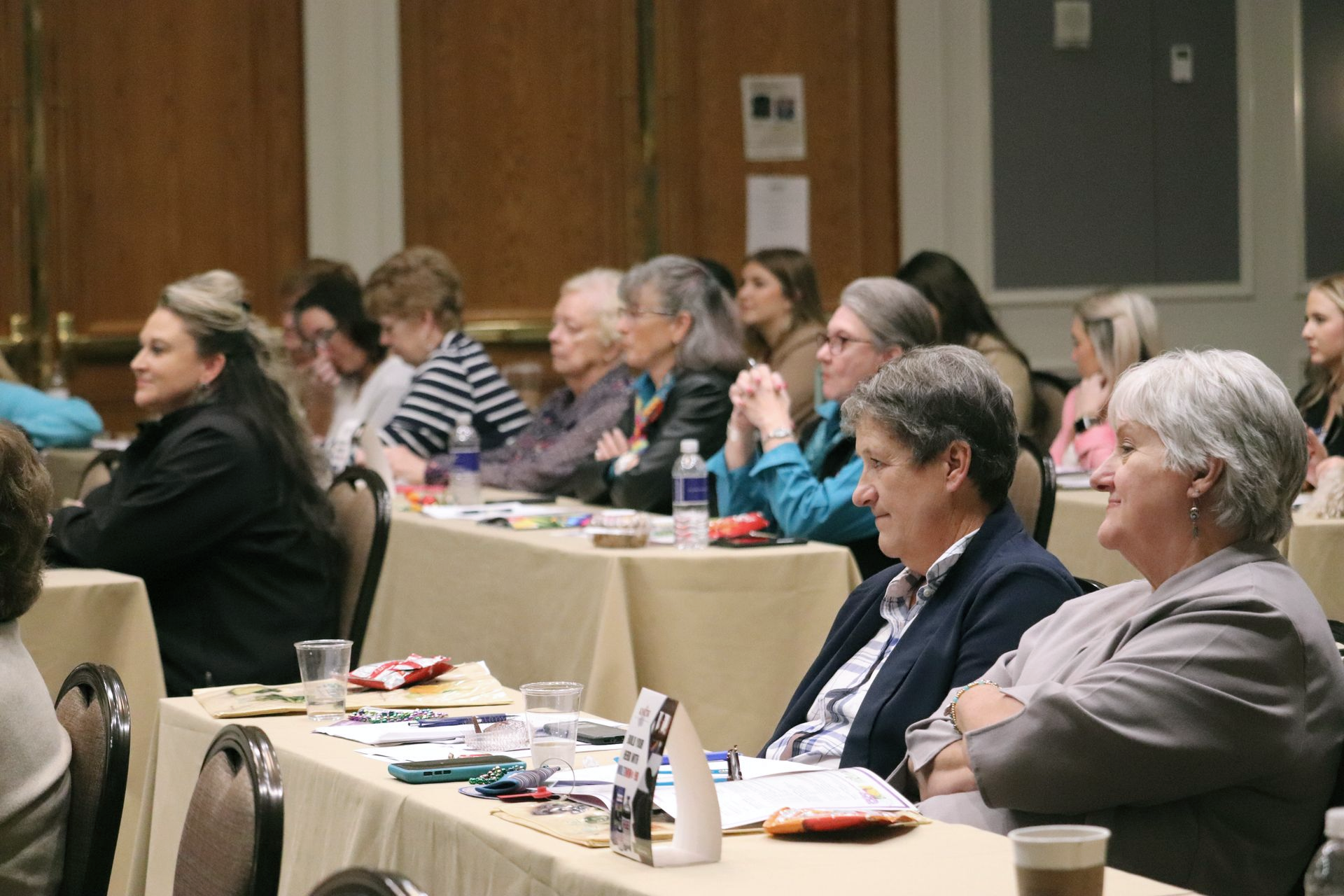 Five women smiling, posing behind illuminated 