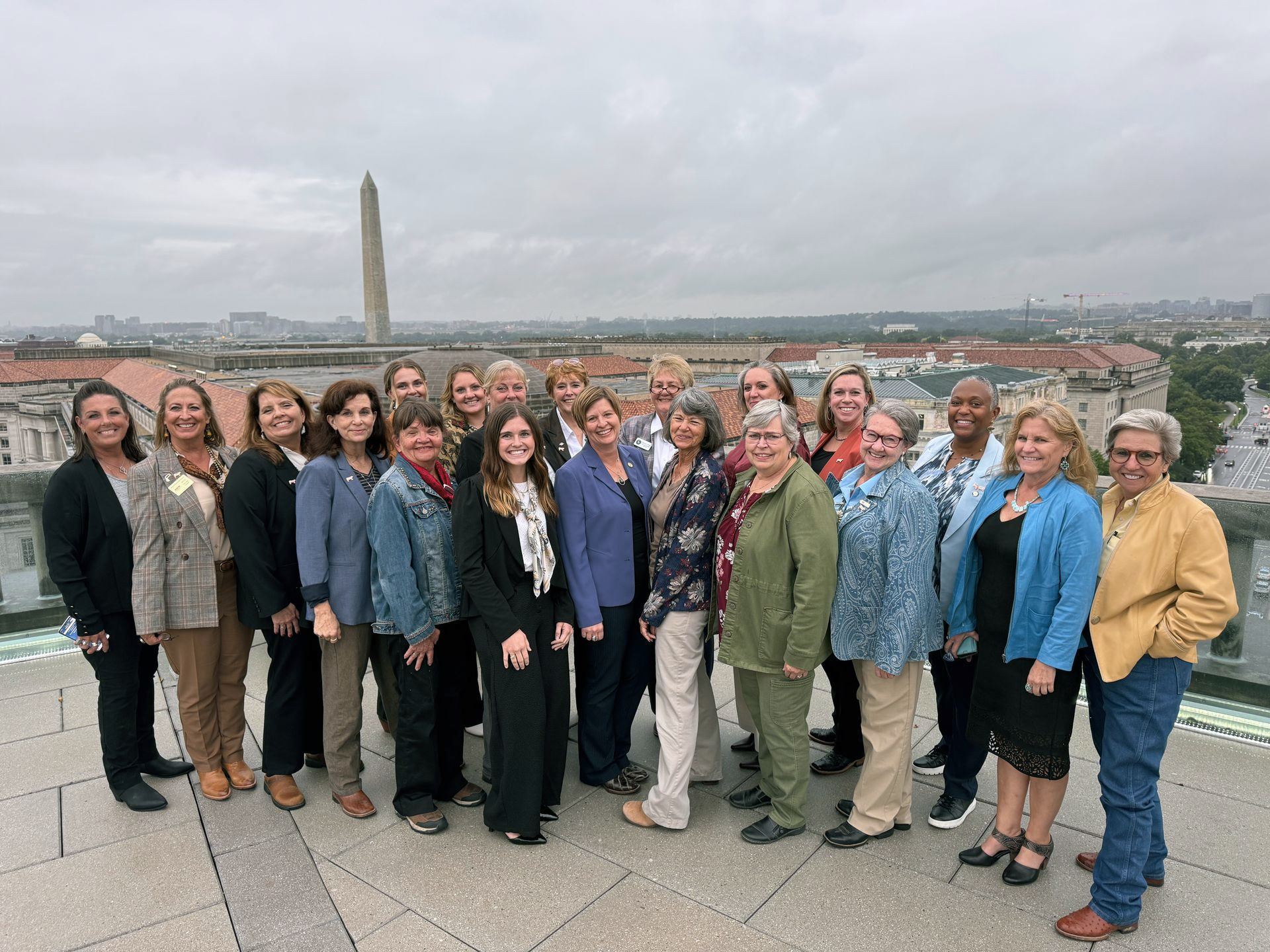 Five women smiling, posing behind illuminated 