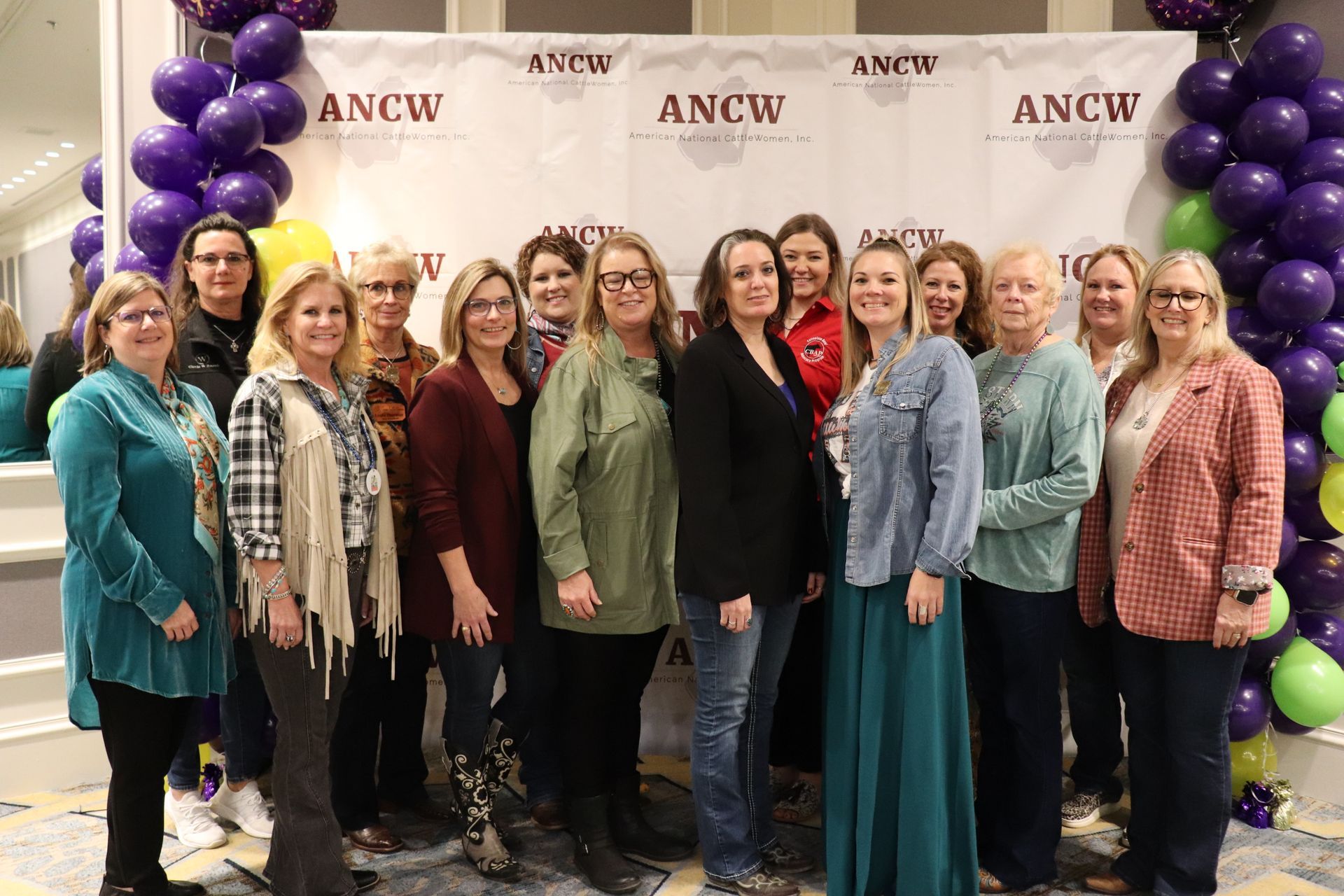 Five women smiling, posing behind illuminated 
