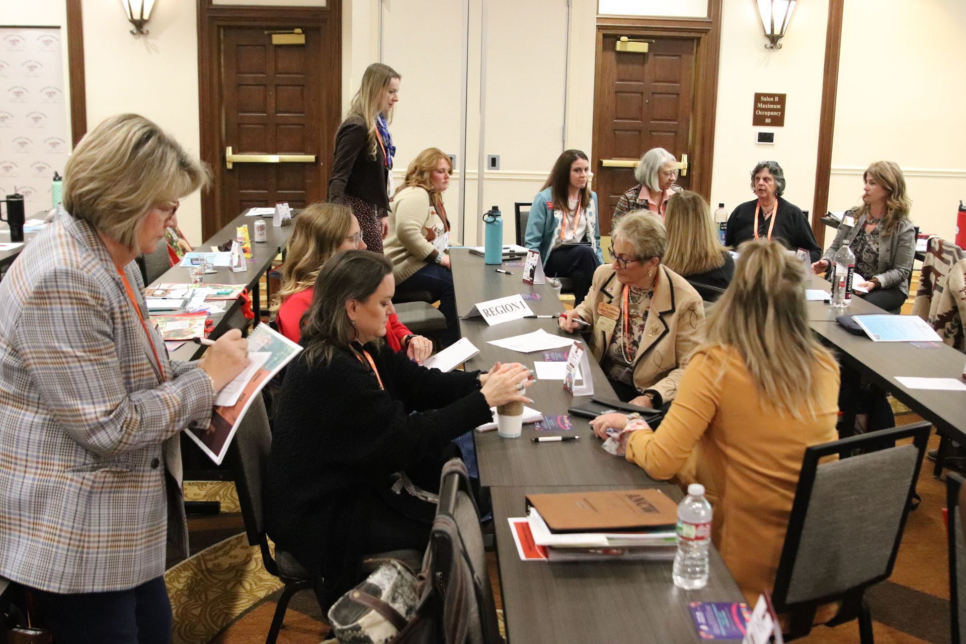 Five women smiling, posing behind illuminated 