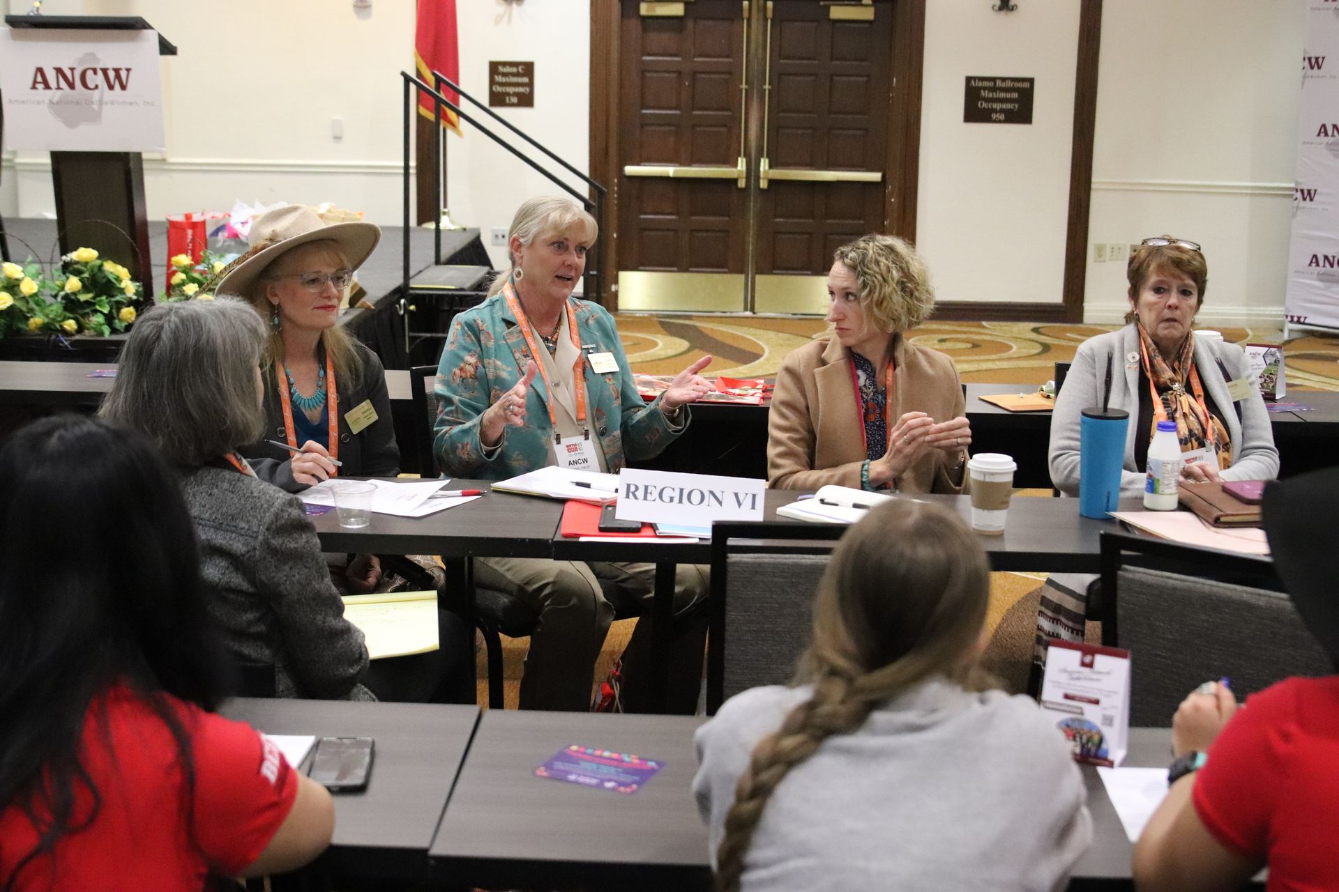 Five women smiling, posing behind illuminated 