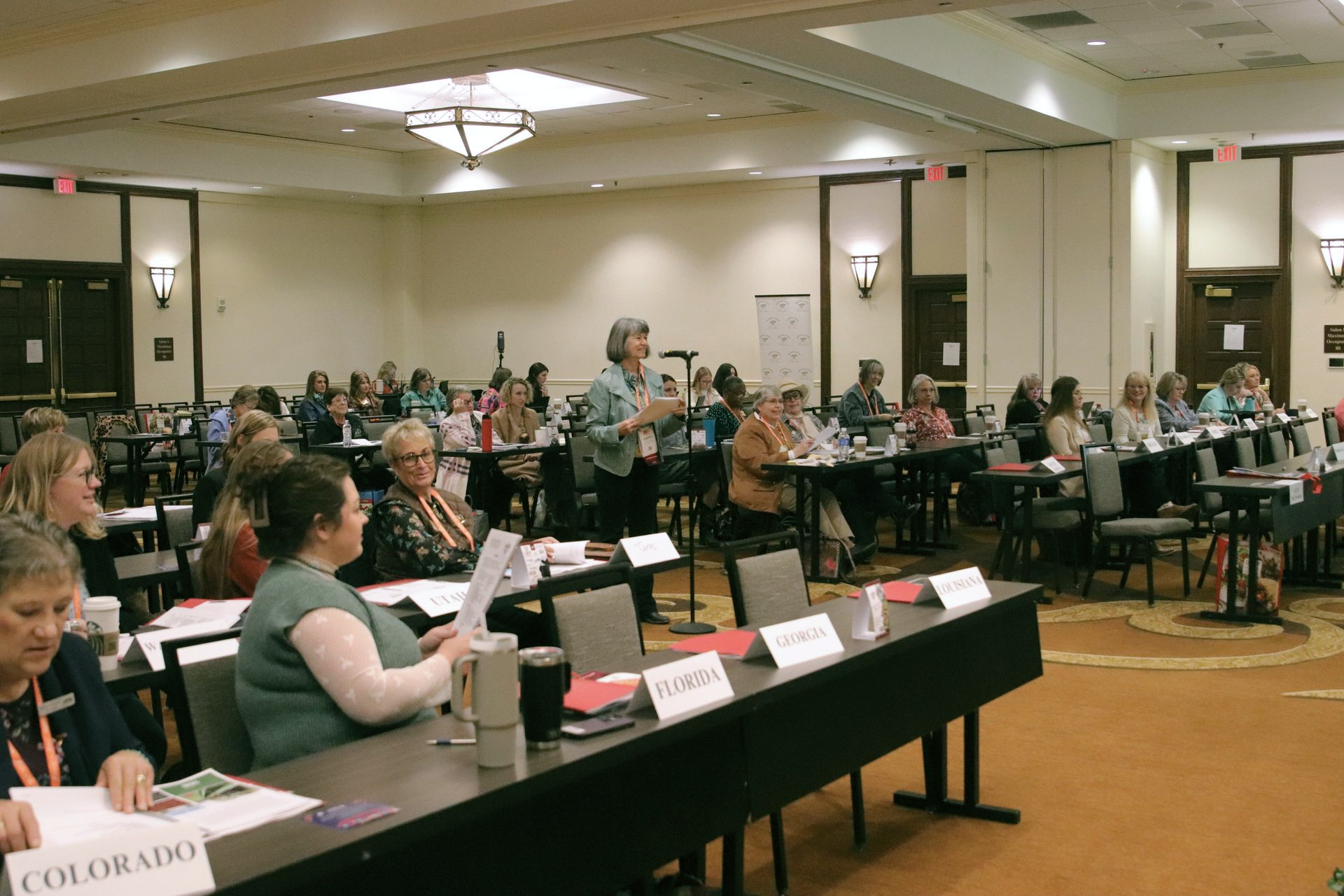 Five women smiling, posing behind illuminated 