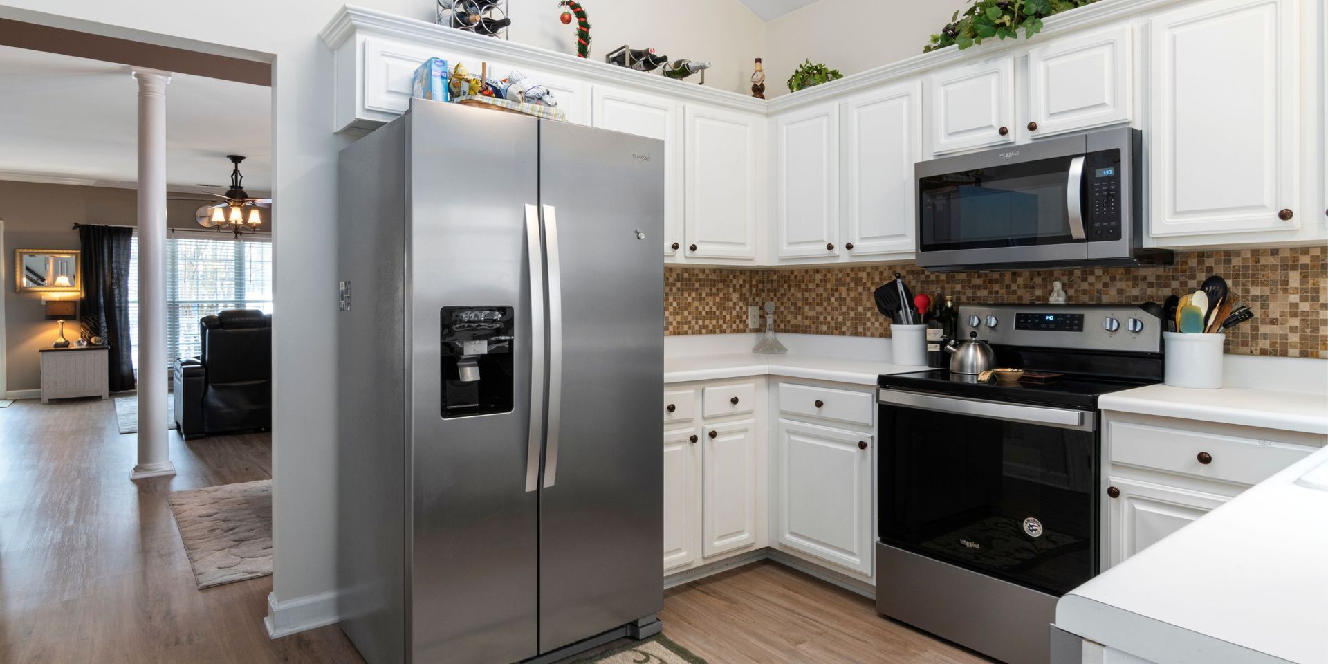Kitchen with white cabinets, stainless steel appliances, and a mosaic tile backsplash.