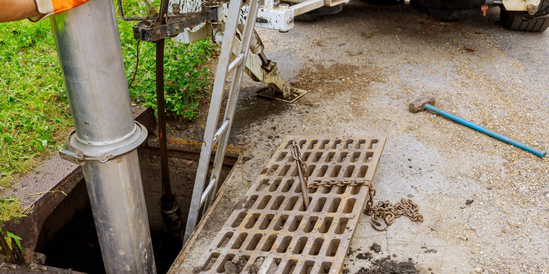 A worker with orange gloves is using a large pipe to work on a sewer.