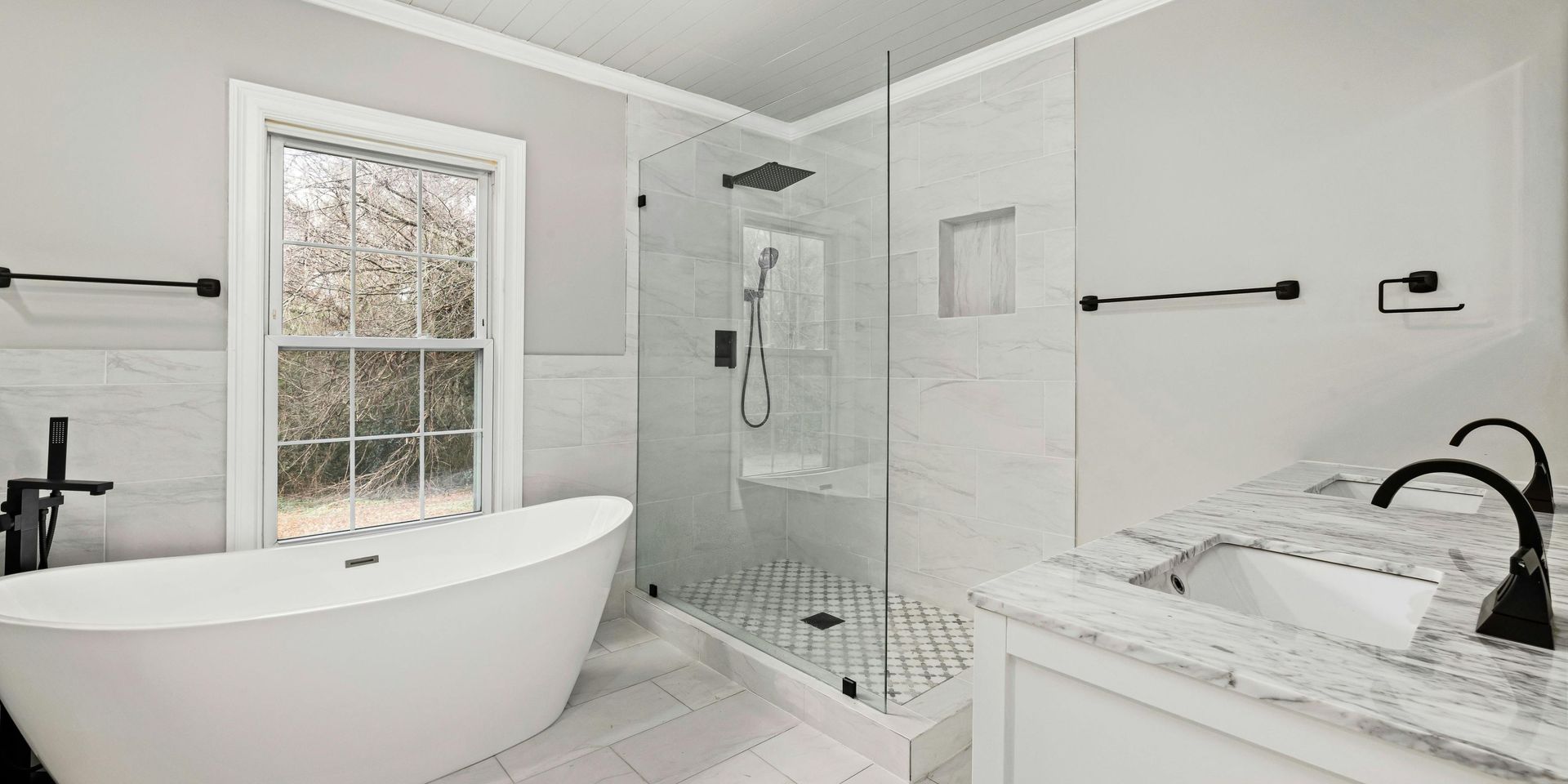Modern white bathroom with a soaking tub, glass shower, and vanity with black fixtures.