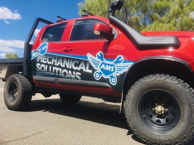 A Red Mechanical Solutions Truck is Parked on the Side of the Road — Bluey's Signs in Ciccone, NT