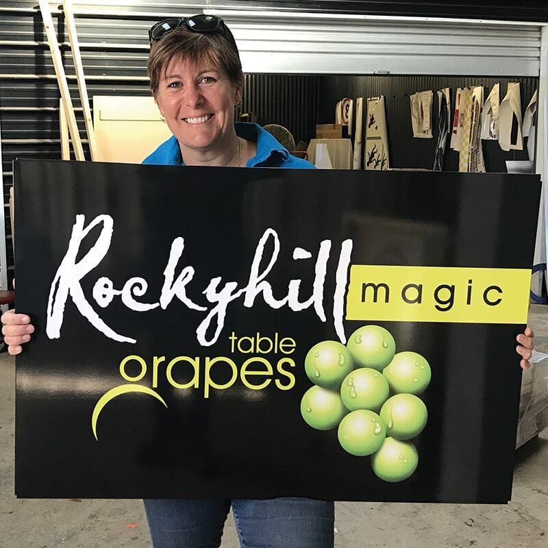 A Woman is Holding a Sign for Rockyhill Magic Table Grapes — Bluey's Signs in Ciccone, NT