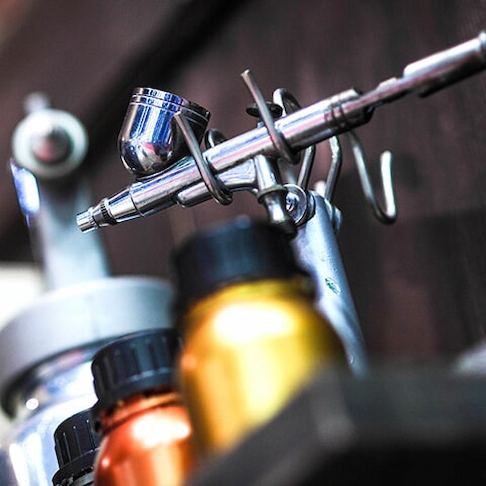 A Close Up of an Airbrush With Bottles of Paint in the Background — Bluey's Signs in Ciccone, NT
