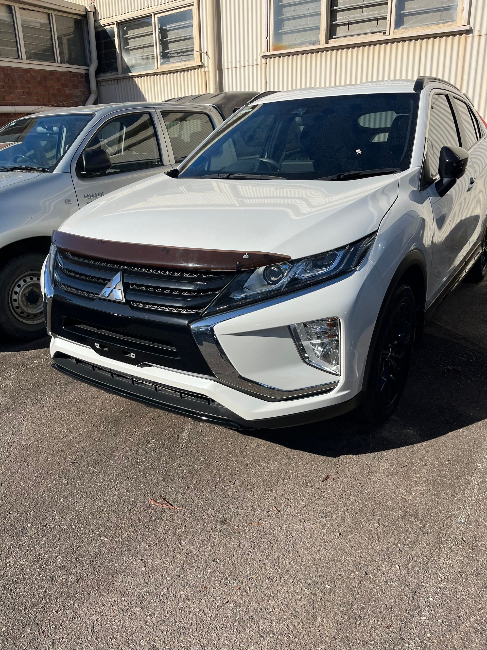 A white Mitsubishi Eclipse cross is parked in front of a building | Autotek New South Wales