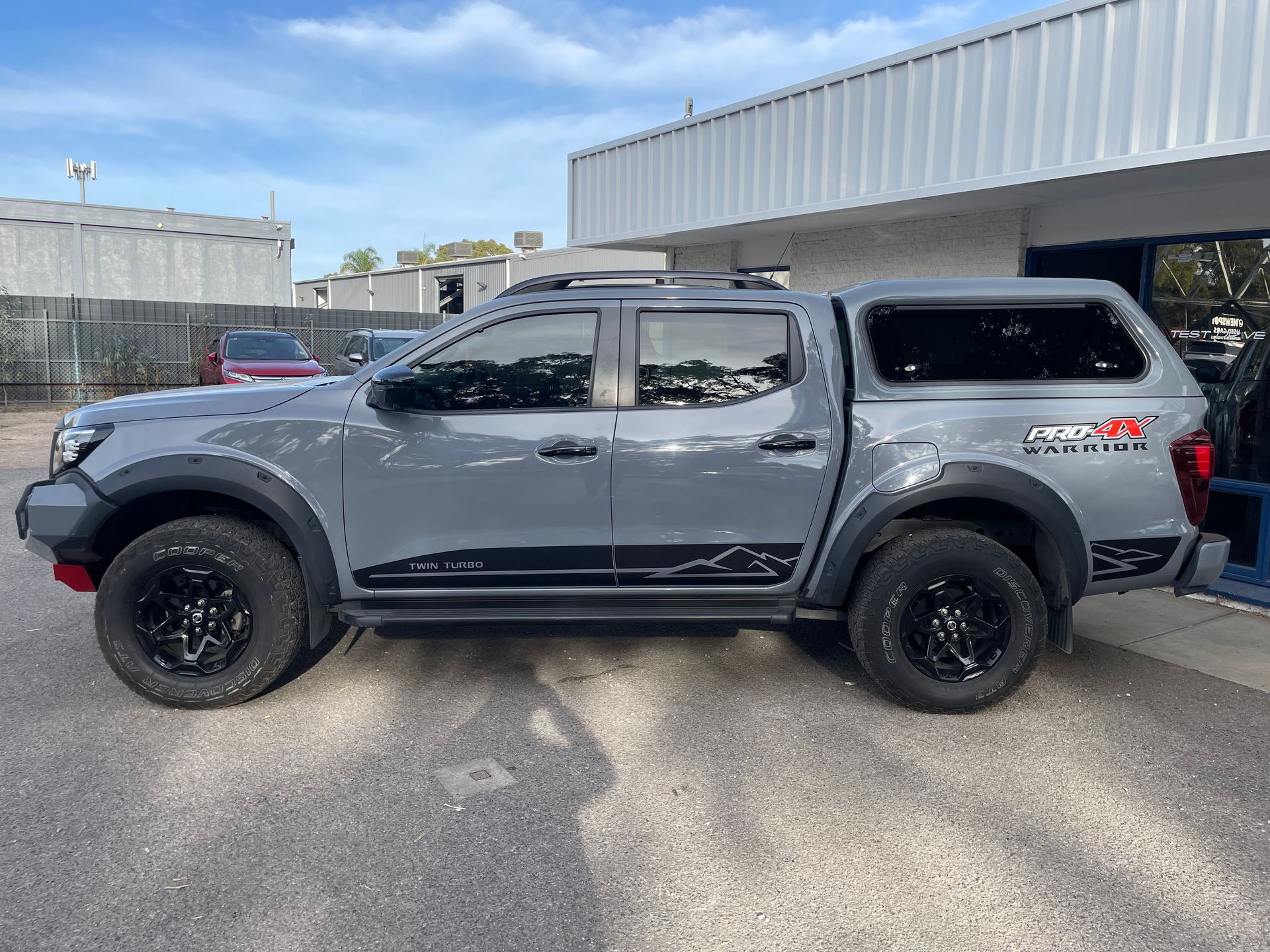 A gray truck with a canopy is parked in front of a building | Autotek New South Wales