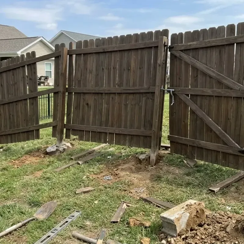 Contractor inspecting fence posts and footing depth during residential gate installation in Oahu Hawaii.