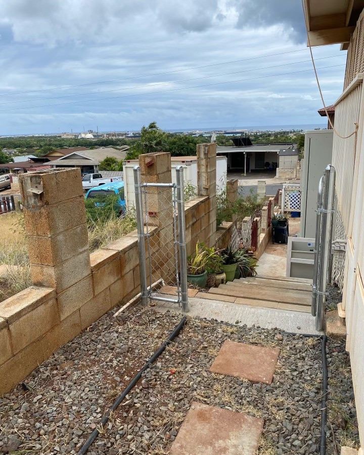 A set of outdoor steps leads uphill between concrete block walls, with a view of a town under a cloudy sky.
