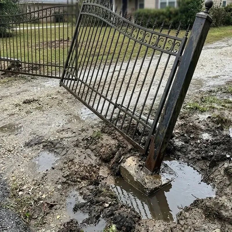 Residential driveway gate installation showing poor drainage causing water pooling around gate post base.