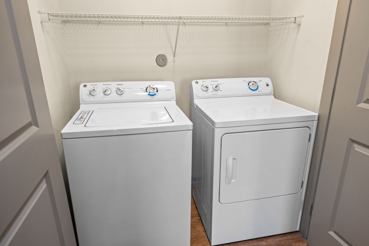 White washing machine and dryer side by side in a small laundry closet.