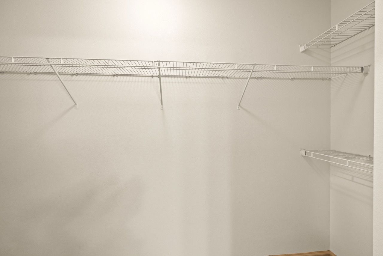Empty walk-in closet with white wire shelving along the walls.
