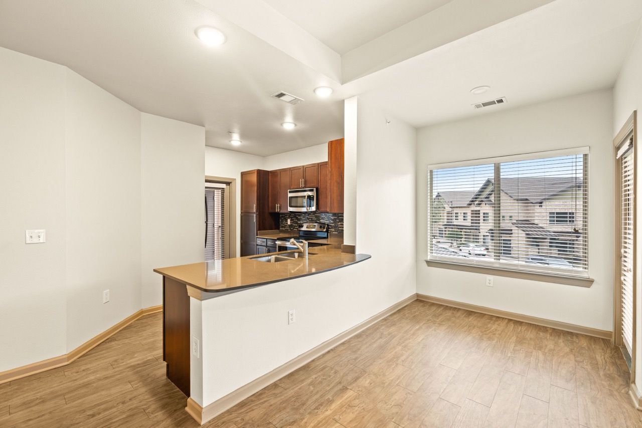 Open-concept kitchen with island, stainless-steel appliances, and a large window in a bright apartment.