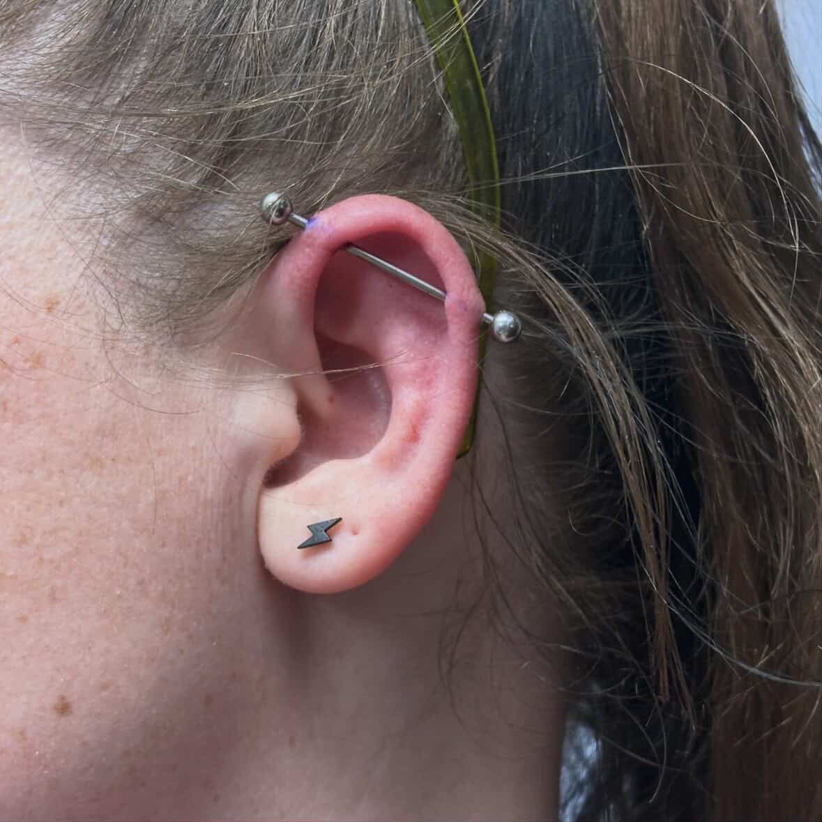 A close up of a woman 's ear with multiple piercings and hoop earrings.