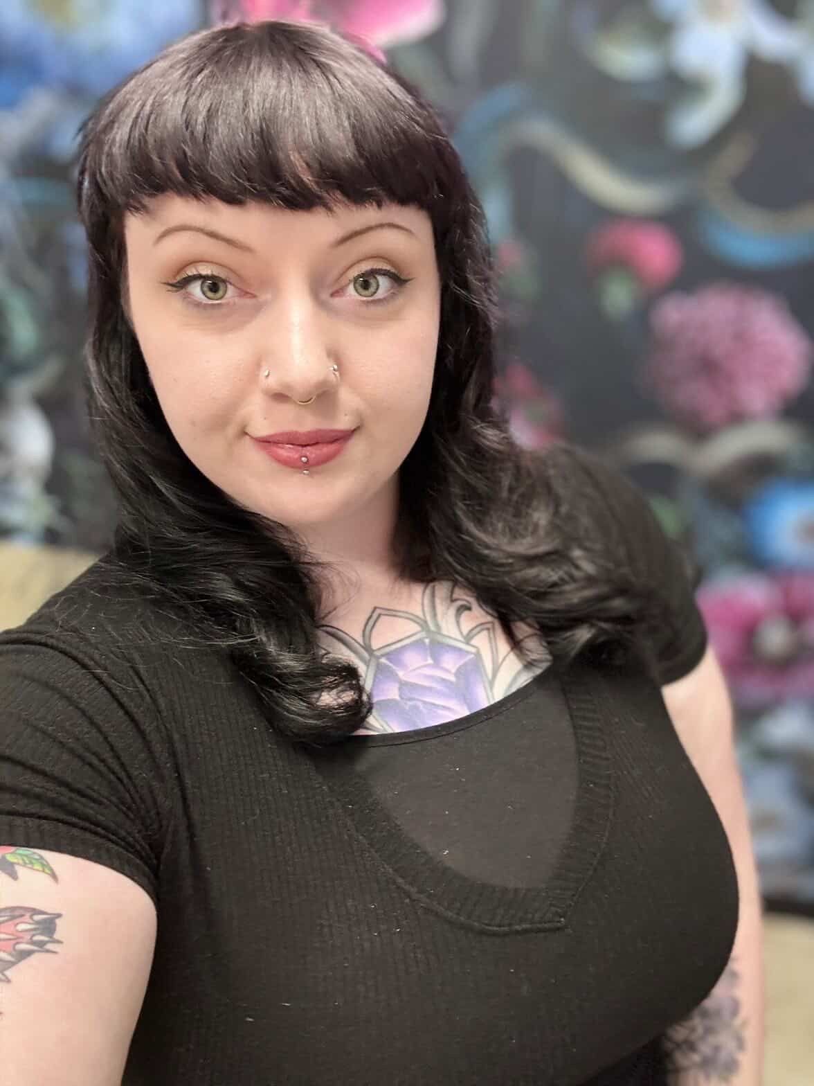 A woman is smiling for the camera while holding a pink purse.