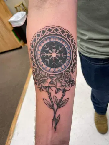 A person has a tattoo of a compass and roses on their forearm.