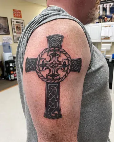 A man has a cross tattoo on his arm.