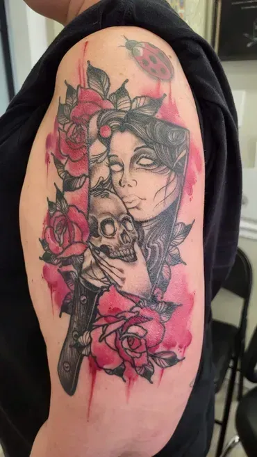 A woman has a tattoo of a woman holding a skull and roses on her shoulder.