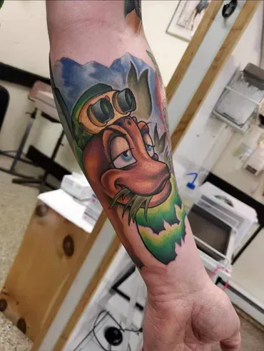 A man has a tattoo of a cartoon character on his forearm