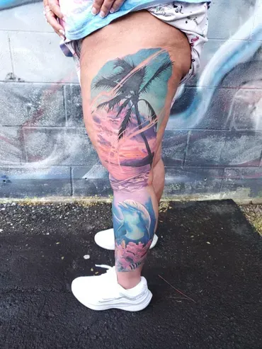 A woman has a colorful tattoo on her leg.