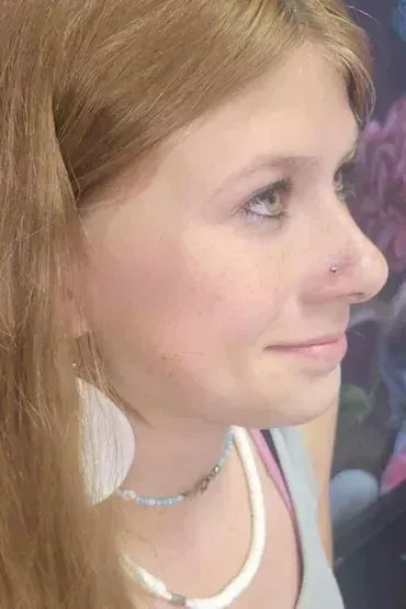 A close up of a woman 's face with a nose ring and earrings.