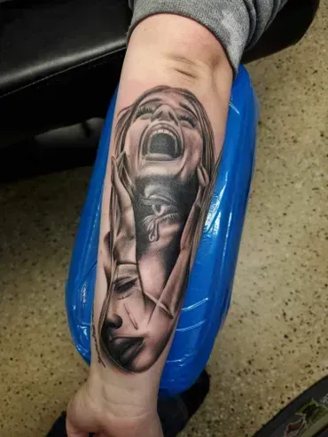 A person has a tattoo of a woman screaming on their arm