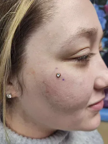 A close up of a woman 's face with a piercing on it.