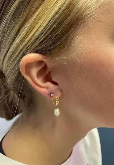 A close up of a woman 's ear with earrings.
