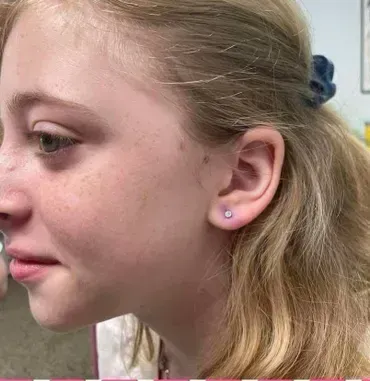 A close up of a girl 's face with earrings in her ears.