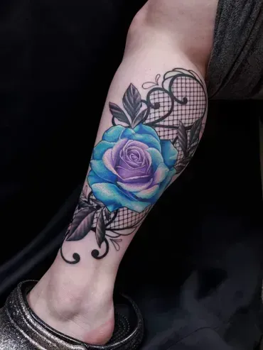 A woman has a blue rose tattoo on her leg.