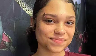 A young woman with a piercing in her eyebrow is smiling for the camera.
