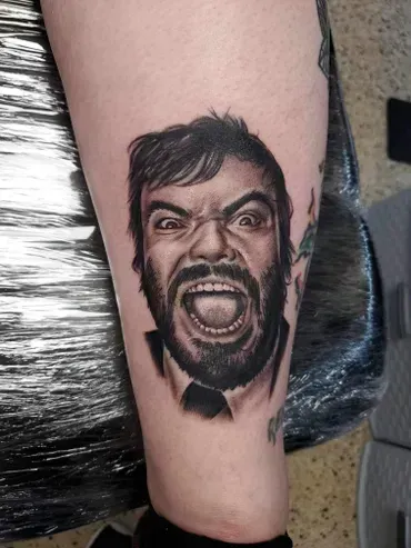 A black and white tattoo of a man with a beard on his leg.
