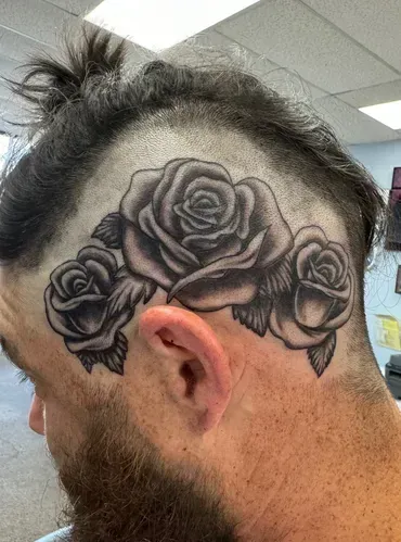 A man has a tattoo of three roses on his head.