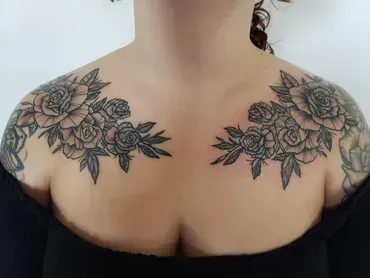 A woman has a tattoo of roses on her shoulder and chest.