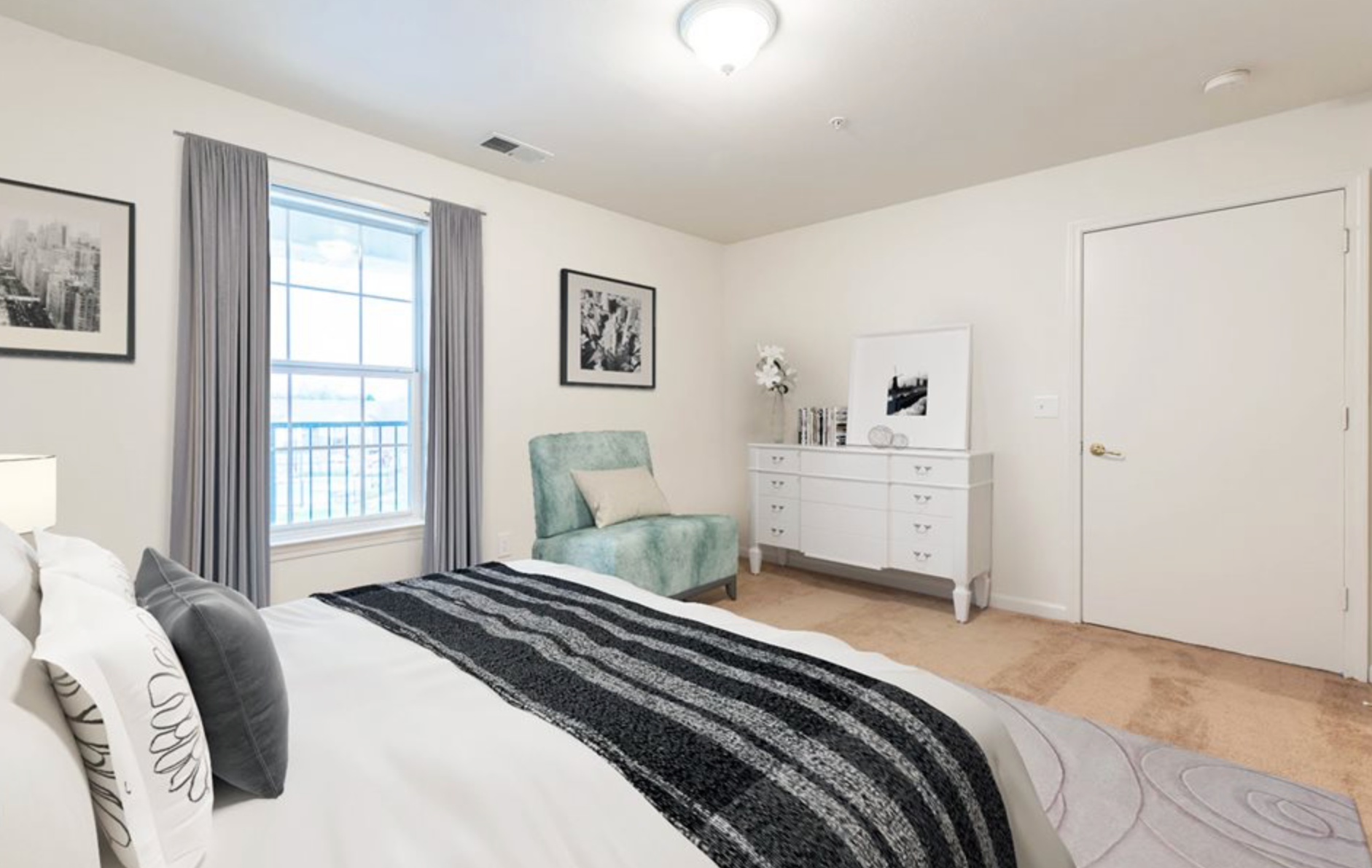 A bedroom with a bed , chair , dresser and window.