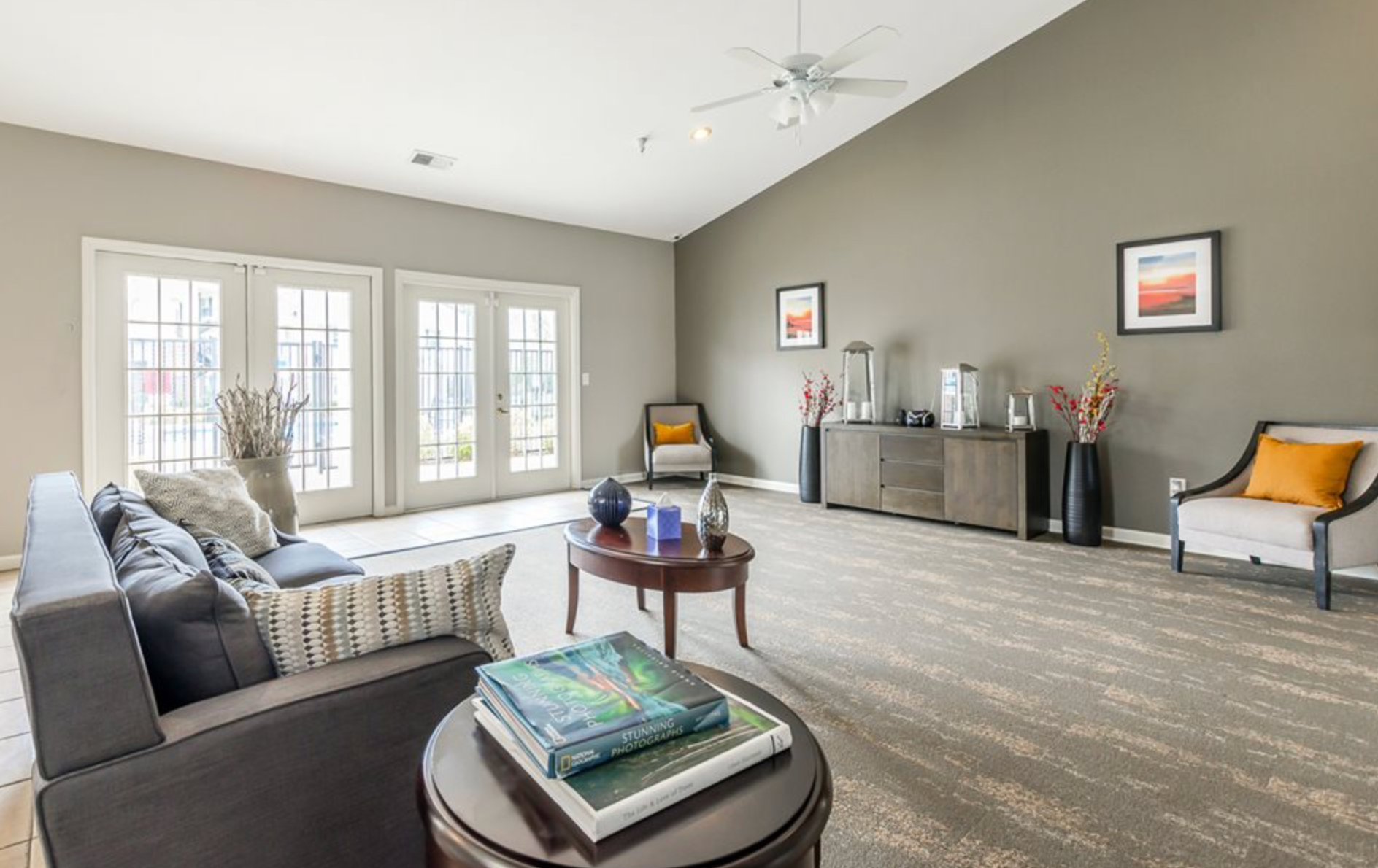 A living room with a couch , chairs , a table and a ceiling fan.