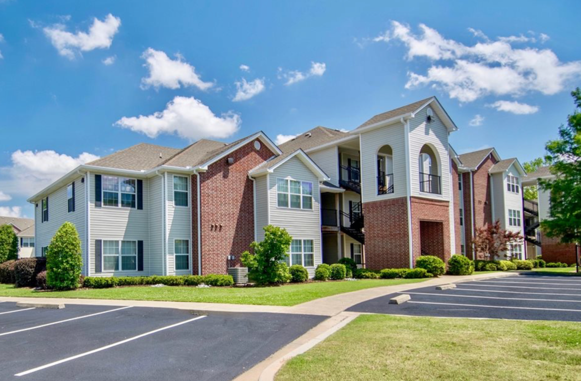 A large apartment building with a lot of windows and a parking lot in front of it.