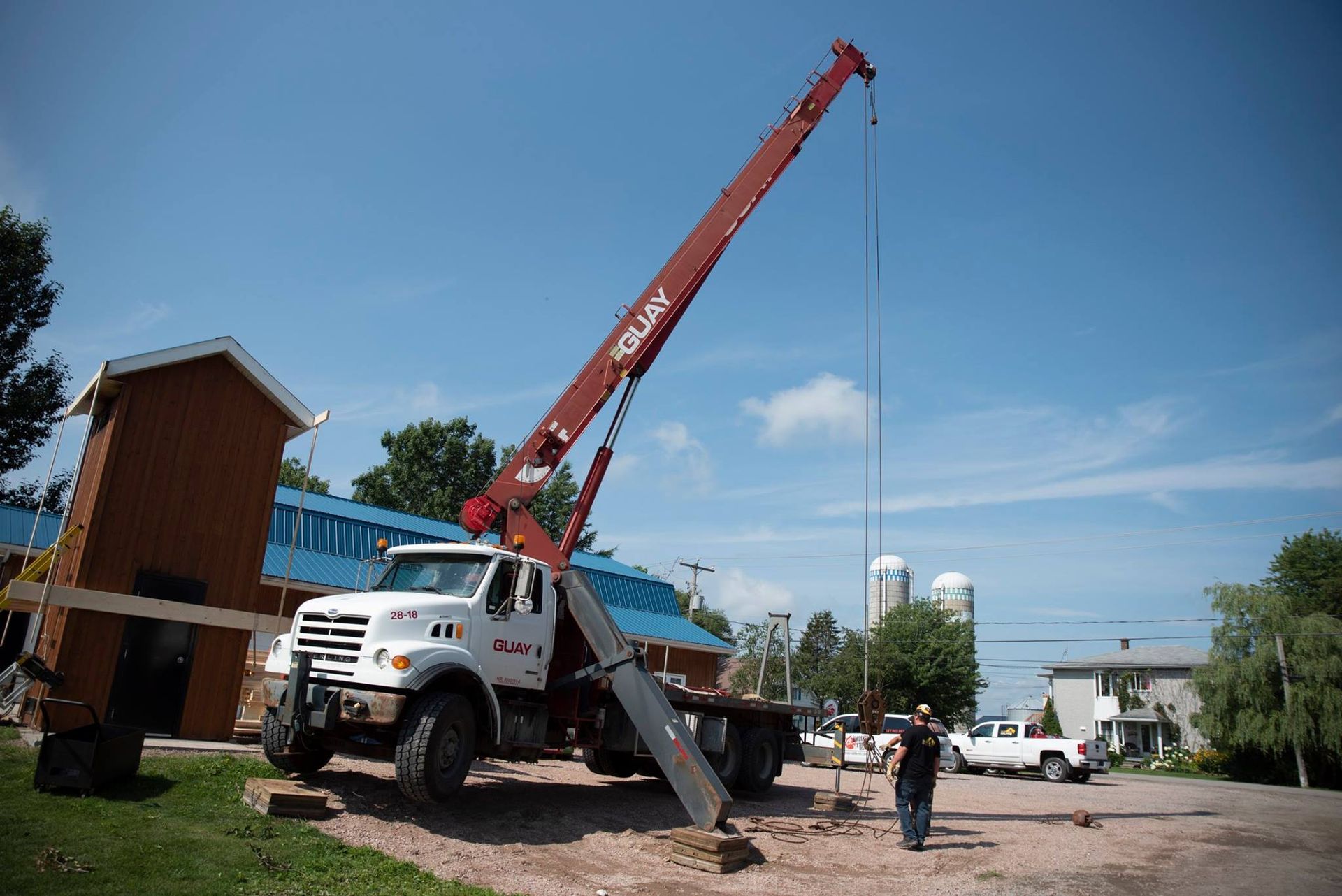 Un camion avec une grue attachée est garé devant un bâtiment.