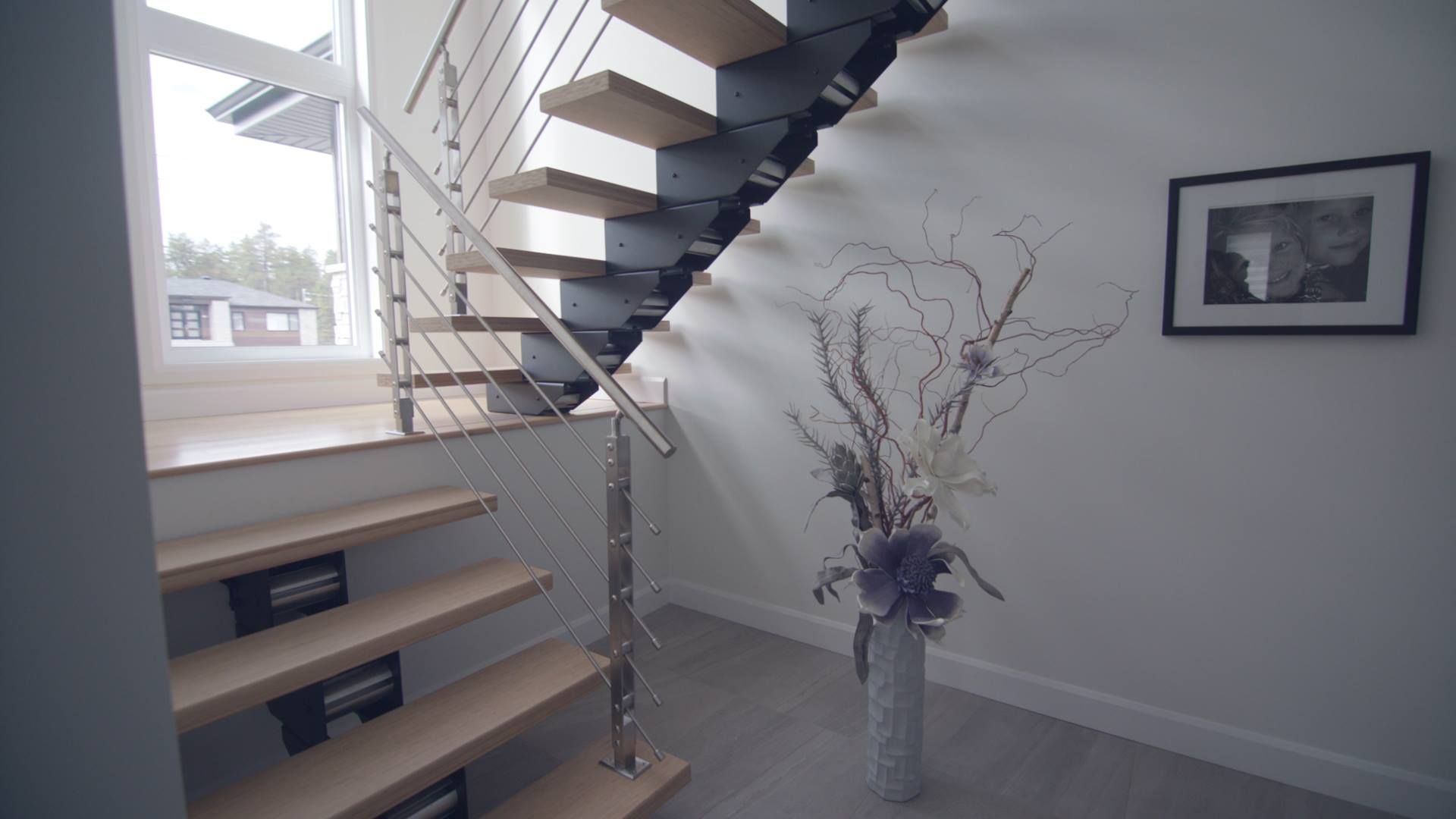 Un escalier dans une maison avec un vase de fleurs sur le sol.