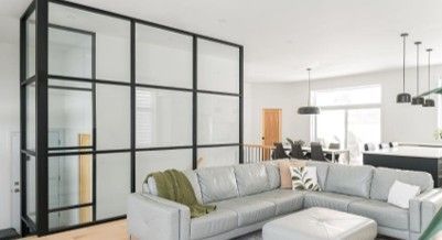 Un salon avec un canapé, un pouf et des murs en verre.