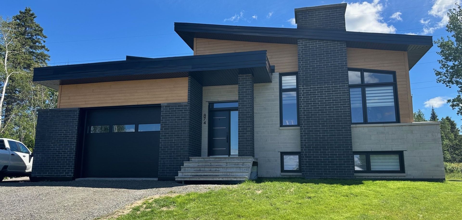 Une maison moderne avec une voiture garée devant.