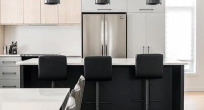 Une cuisine avec des armoires blanches, un réfrigérateur en acier inoxydable, une table et des chaises.