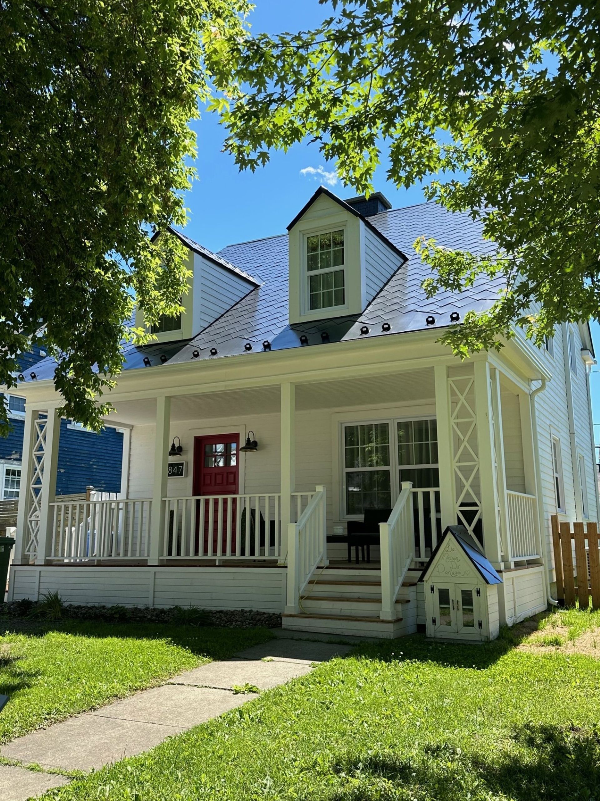 Une maison blanche avec un toit bleu et une porte rouge