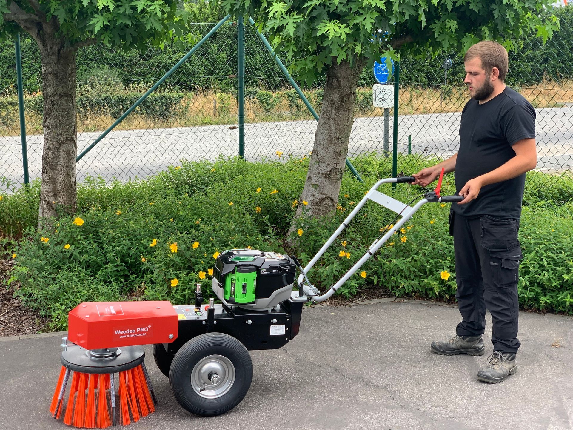 Man working with the Weedee PRO®. He is using it on a road, removing the weeds.